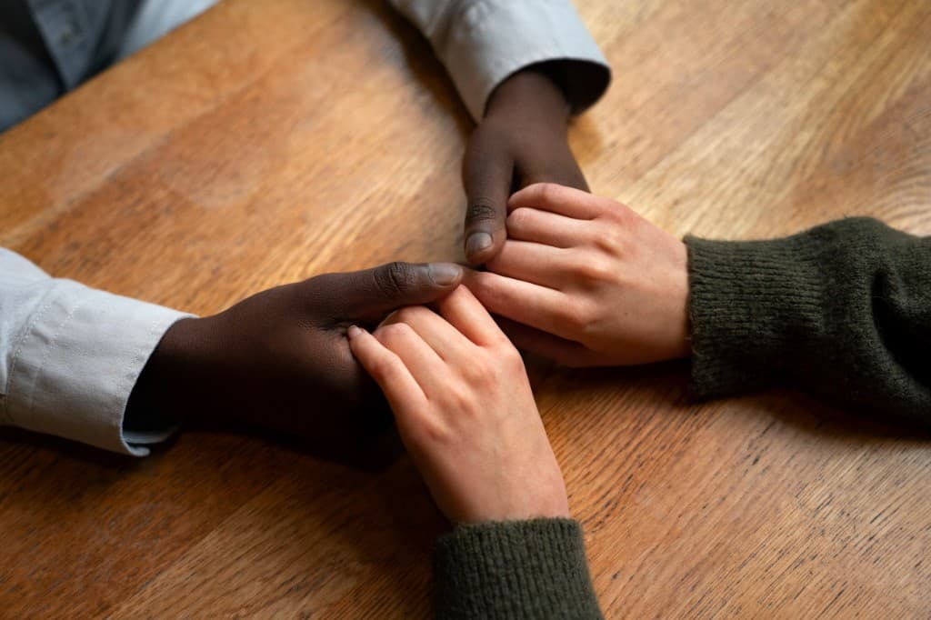 Two people holding hands in support across a table